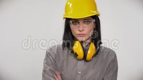 戴眼镜戴头盔和戴耳机的年轻建筑工人的肖像双手交叉严肃白色视频的预览图