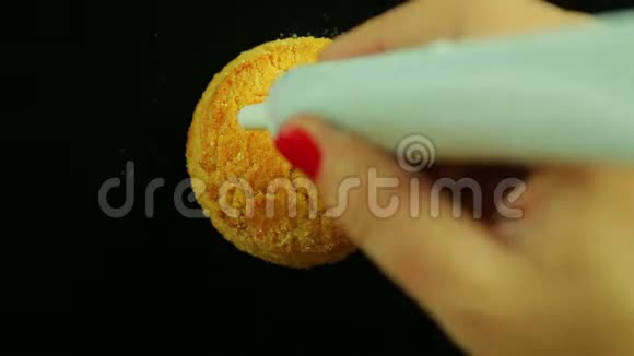 一只雌性手拿着一管炼乳在饼干上画着滑稽的表情符号时间跨度视频的预览图