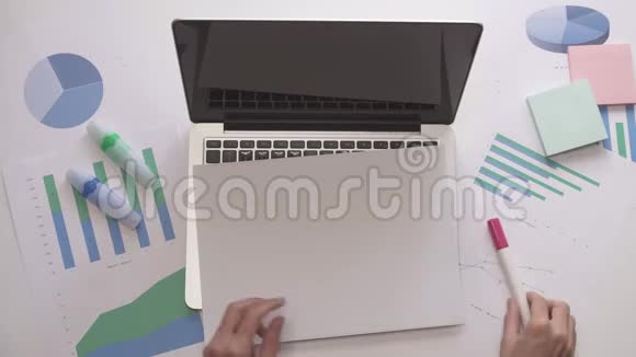女人在笔记本电脑上的一张纸上画增加的图表办公室桌面视频的预览图