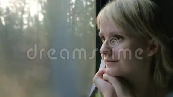 一个旅行女人的肖像坐在火车的车窗旁视频的预览图