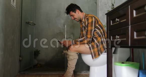 男人坐在厕所用手机年轻人上网聊天视频的预览图