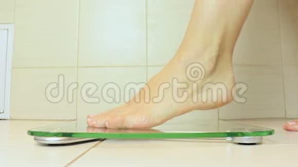 女人光着脚站在秤上在浴室里称重饮食和减肥概念视频的预览图
