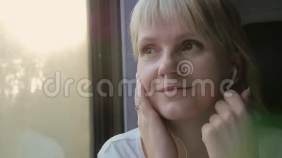 迷人的女人坐火车旅行听耳机音乐视频的预览图