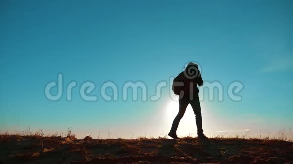 一个值得去旅游的男人背着背包的阳光站在山顶上捡起一只小狗慢速视频视频的预览图