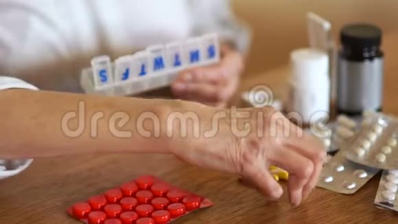 一位老妇人的手把她的药丸折叠在一个塑料组织者一个药片的容器里药学概念关节炎视频的预览图