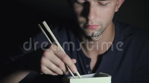 一个从盒子里拿筷子吃面条的男人的特写欧洲人吃中国菜视频的预览图