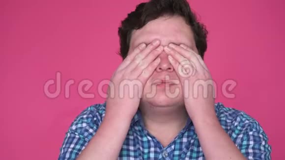 年轻人用手捂住眼睛孤立于粉红色背景视频的预览图