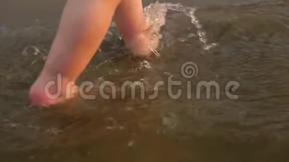 小孩子沿着河岸走第一步把水溅到两边腿特写镜头慢动作视频的预览图