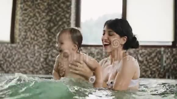 妈妈和女儿在游泳池里溅水做母亲的快乐时刻视频的预览图