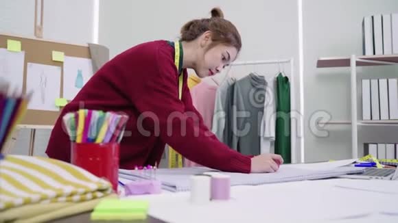 年轻的亚洲女性时装设计师用铅笔画画在工作室工作时看着纸视频的预览图