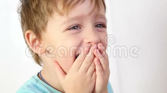 用手闭上嘴的小孩的特写男孩表现出快乐和微笑积极的情绪视频的预览图
