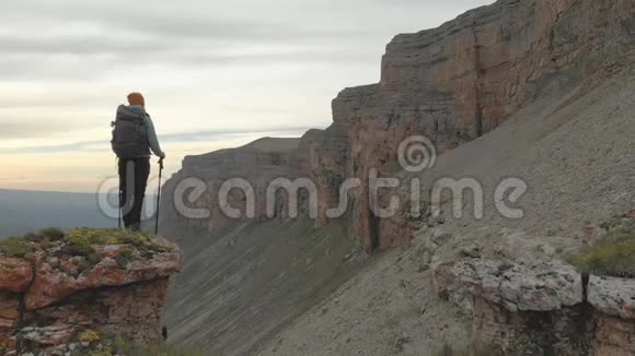 从一个年轻的成年女子手背背包回到史诗脚下的岩石顶部视频的预览图