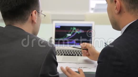 高级经纪人向他的初级同事解释笔记本电脑屏幕上的图表视频的预览图