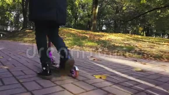 在秋天公园女学生用滑板车在人行道上行走视频的预览图
