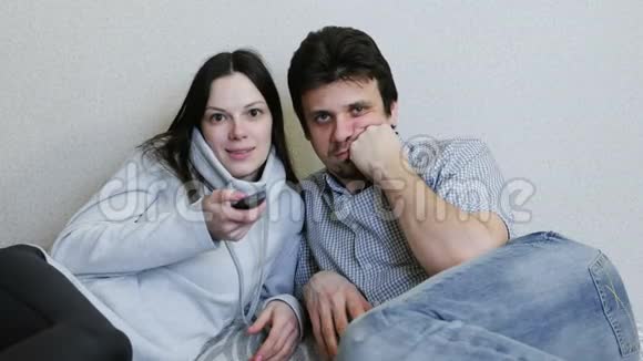 两个人躺在沙发上看电视男人亲吻女人的脸颊视频的预览图