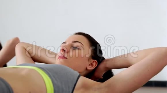 两个女人特写仰卧着做腿抬高的仰卧起坐普拉提训练视频的预览图
