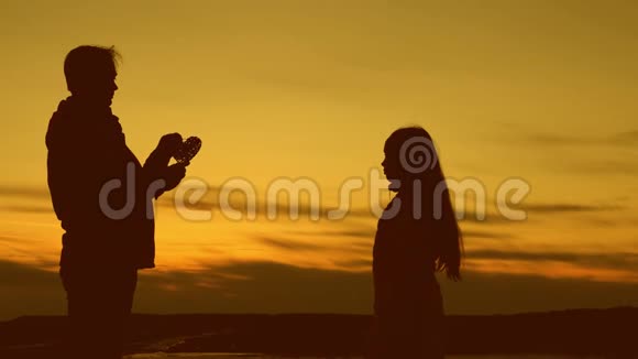慈爱的父亲与女儿牵着心在他们的手哀悼日落的太阳视频的预览图