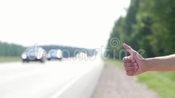 前景是一只拇指向上的手向过往车辆发出信号的手视频的预览图