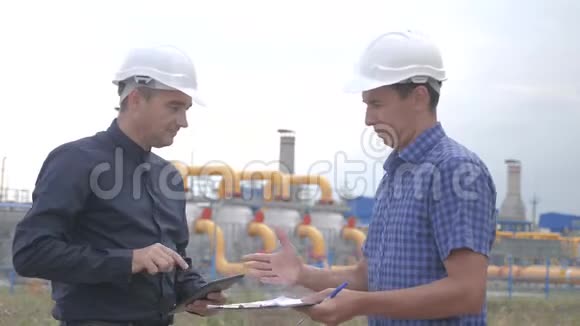 团队合作制气站理念慢动作录像两名戴头盔的工程师在天然气供应上握手视频的预览图