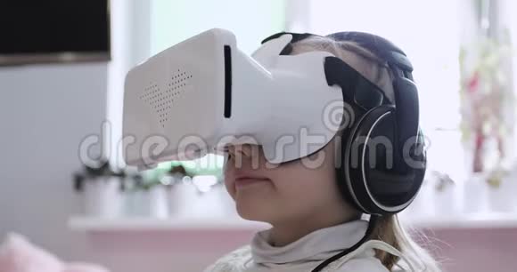 一个快乐的小女孩正在看耳机和虚拟现实眼镜里的卡通视频的预览图