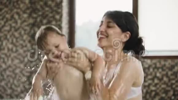 妈妈和女儿在游泳池里溅水做母亲的快乐时刻视频的预览图