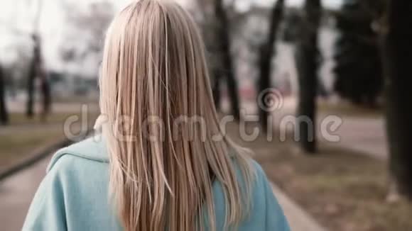 后景金发女人走着向左看穿着蓝色外套的白人女孩美丽的长发慢动作视频的预览图