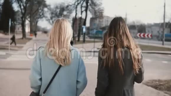 两个女朋友一起在街上散步年轻女士穿着整洁时尚的衣服在城市环境中后景视频的预览图