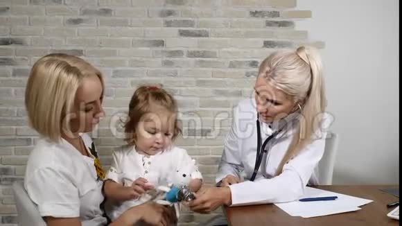儿童健康检查年轻的母亲和她漂亮的小女儿去看家庭医生友好的儿科医生视频的预览图