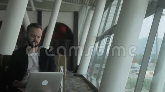年轻男性旅行者的肖像他正在机场里看着笔记本电脑的屏幕视频的预览图