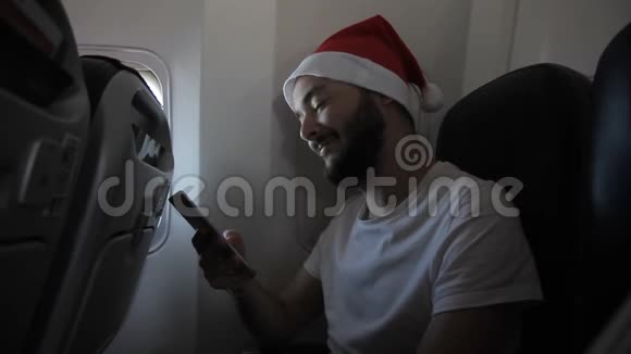 年轻人的肖像他正在飞机上用他的智能手机打字视频的预览图