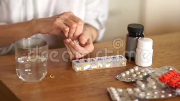 退休人员用玻璃杯里的水冲洗一片药片药学概念一个老女人的手在视频的预览图