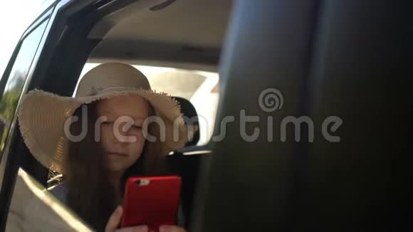 带着草帽的女孩用智能手机分享社交媒体公路旅行概念视频的预览图