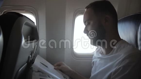 男乘客的肖像他正在现代飞机上阅读杂志视频的预览图