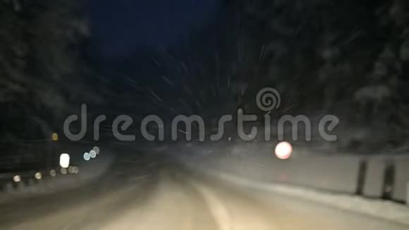 我们在夜间沿着一条雪道穿过一片冬林注意挡风玻璃上的雪花视频的预览图