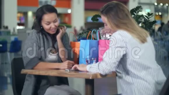 两个女人在商场的咖啡馆里用智能手机视频的预览图