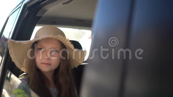 快乐美丽的女孩带着草帽在汽车后座旅行公路旅行概念视频的预览图