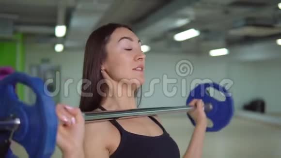 健身理念漂亮的黑发女人用杠铃锻炼手臂视频的预览图