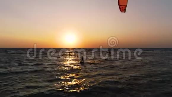 dron在空中飞翔并在黎明时摘下一群控制在海里训练风筝的风筝视频的预览图