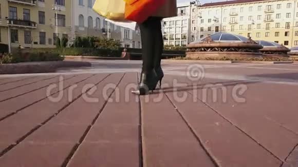 美丽的金发女孩戴着太阳镜带着购物袋在城市里散步视频的预览图