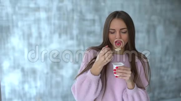 女人吃酸奶慢动作漂亮的年轻女人吃酸奶节食的年轻女人吃白色酸奶可爱视频的预览图