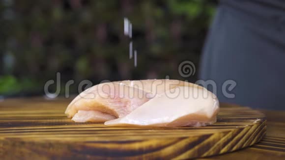 生鲜鸡片肉放在木桌上凑合盐倒在鸡胸肉上躺在厨房的木板上流程视频的预览图