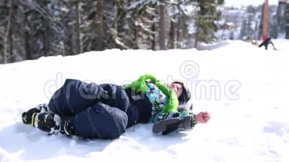 一个小孩在冬天的公园里玩雪躺在白色蓬松的雪上微笑的婴儿新鲜的乐趣和游戏视频的预览图
