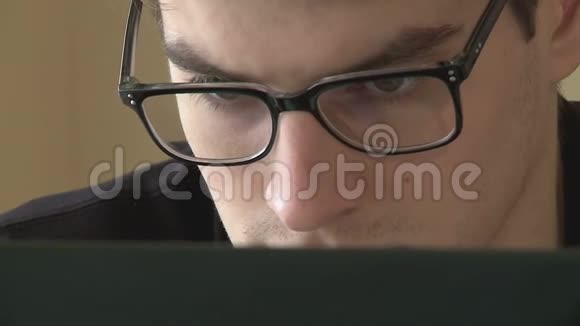 一个戴眼镜的年轻人看着电脑显示器的特写镜头视频的预览图