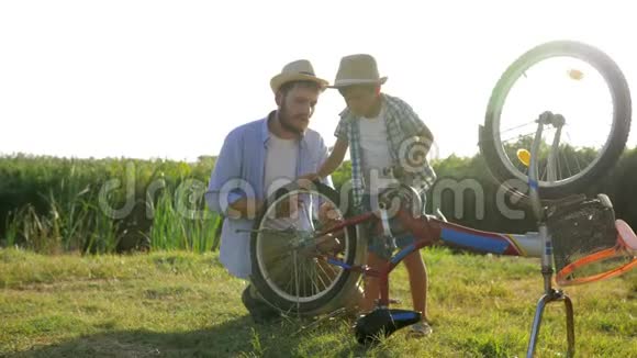 家庭休闲孩子和父亲在乡村的背景下在背光下修理自行车视频的预览图