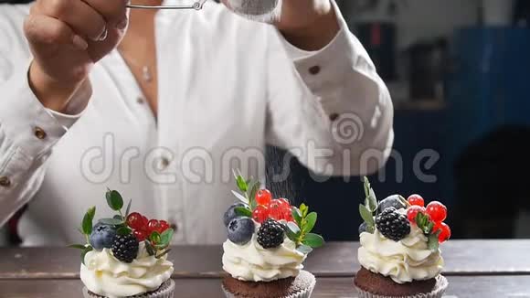 面包师装饰美味的纸杯蛋糕把糖洒在蛋糕上视频的预览图