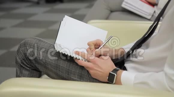 这位商人用笔记本和笔在右手边记会议笔记视频的预览图