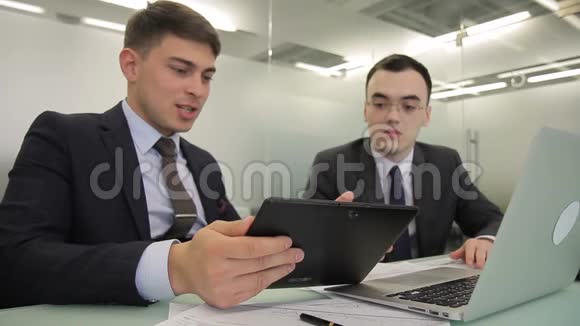 年轻人说话在大公司使用笔记本电脑和平板电脑视频的预览图