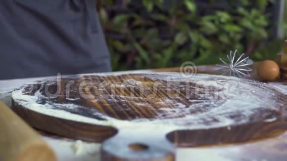 面包师把一把面粉倒在木板上把面团揉在木桌上手工厨师做蛋糕面团视频的预览图