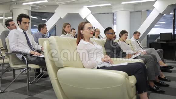 年轻的专业人士在大型公司室内的每周会议上视频的预览图