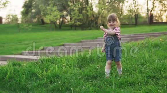 阳光明媚的夏日公园快乐的小女孩在草地上奔跑视频的预览图